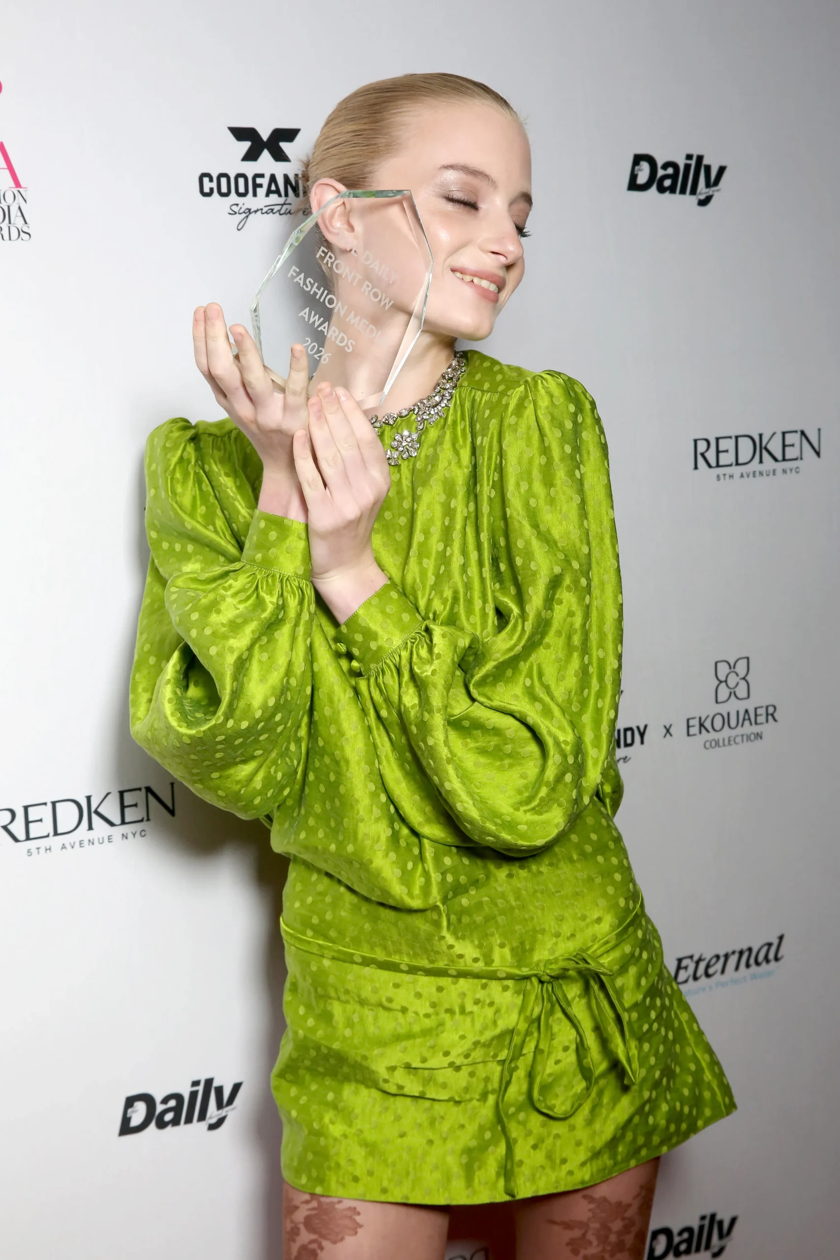 Kai Schreiber holding the crystal Daily Front Row Fashion Media Awards 2026 award, dressed in a green polka dot outfit.