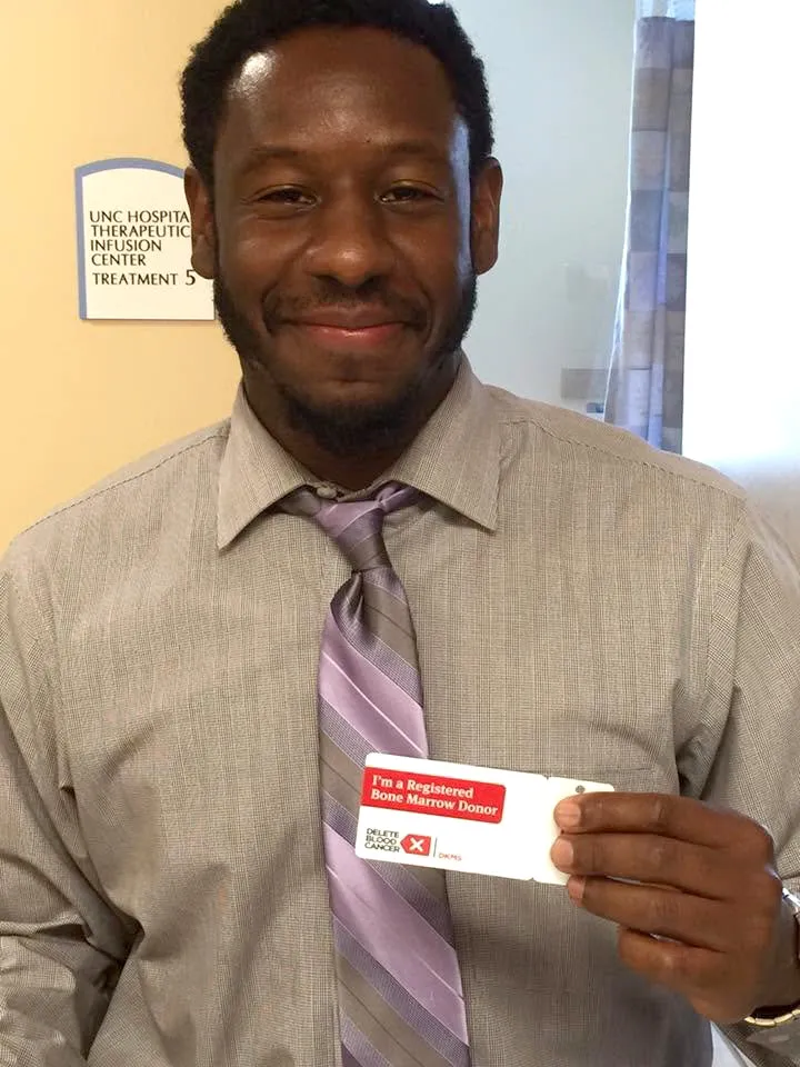 Michael Desronvil holding his bone marrow donor registration card.