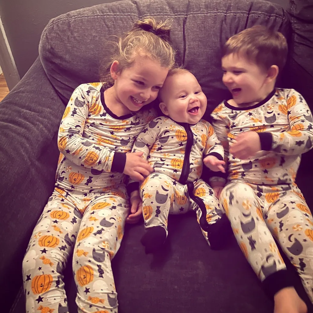 Lindsay Clancy's children, Cora, Callan, and Dawson Clancy, wearing matching Halloween pajamas.