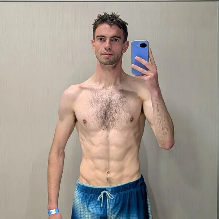 A shirtless man taking a mirror selfie.
