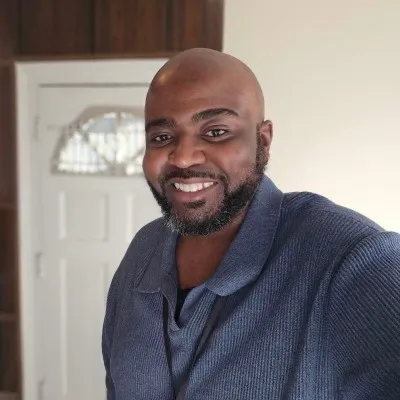 Portrait of Hassan Jihad Ibn Kariem smiling indoors.
