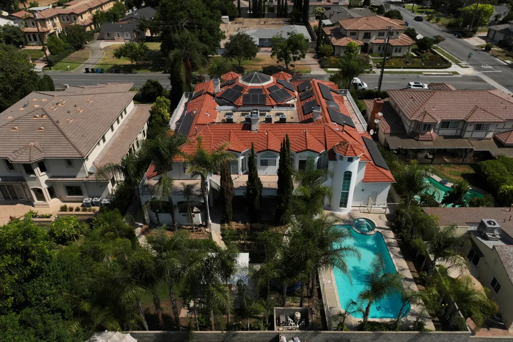 An aerial view shows a large home with a red tile roof, solar panels, and a swimming pool in Arcadia, Calif.