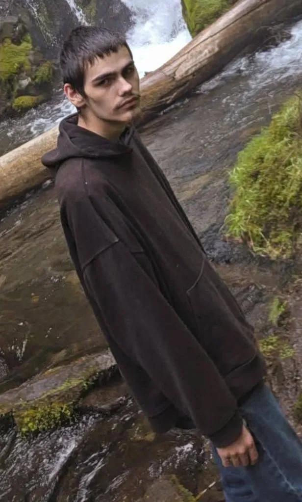 Photo of Griffin J. John standing outdoors near a waterfall.