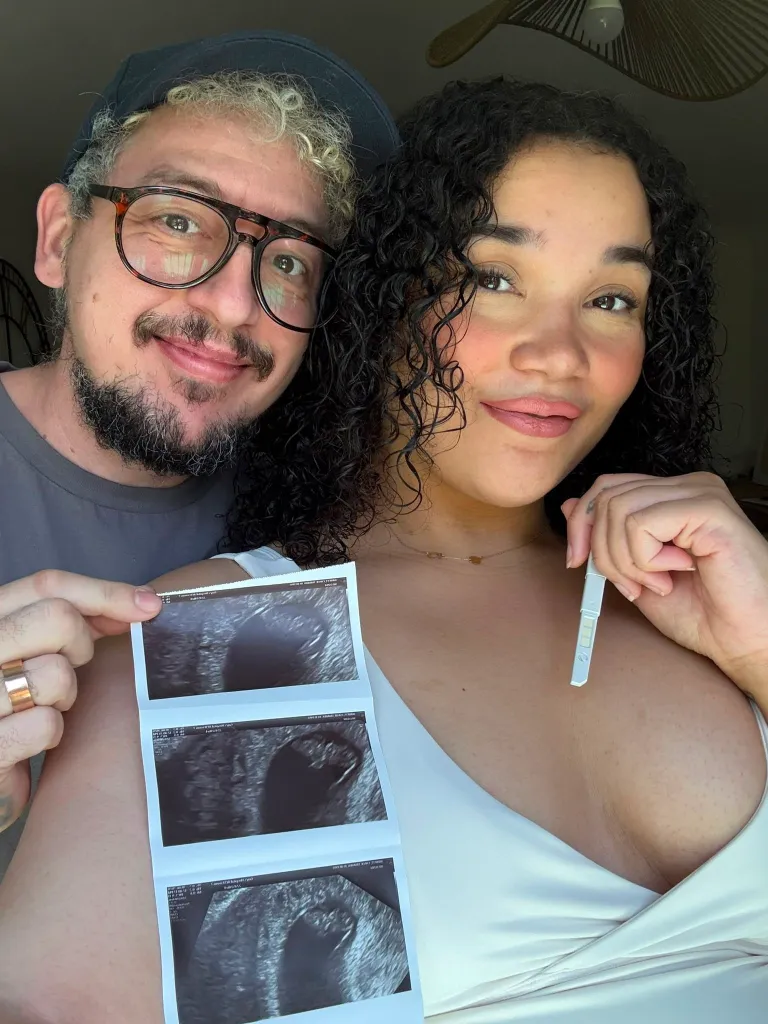 Transgender man Taylor Winters and his wife Chloe pose with a strip of ultrasound scans and a positive pregnancy test.