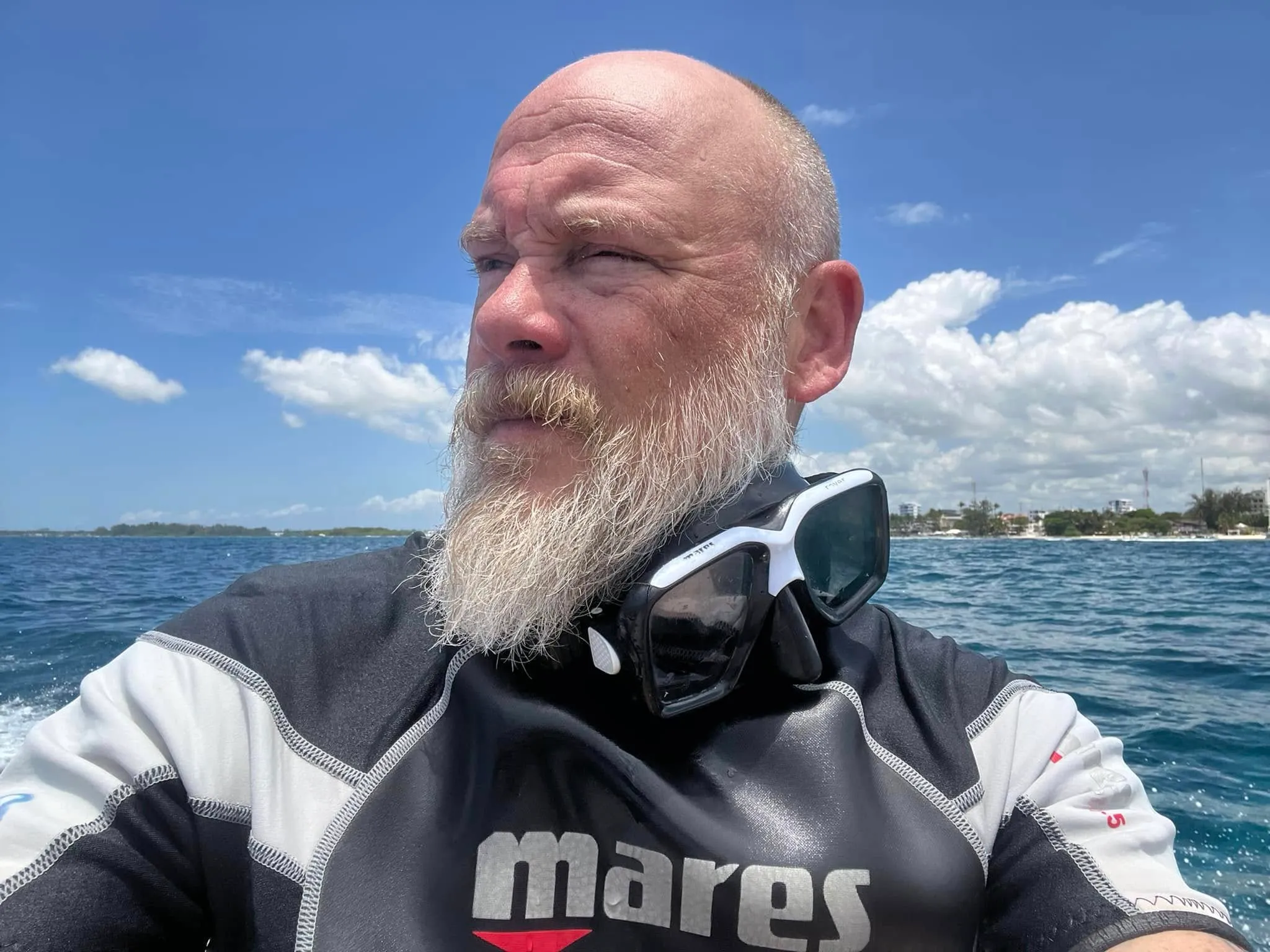 Bryan Seaver wearing a wetsuit and diving mask around his neck on a boat.