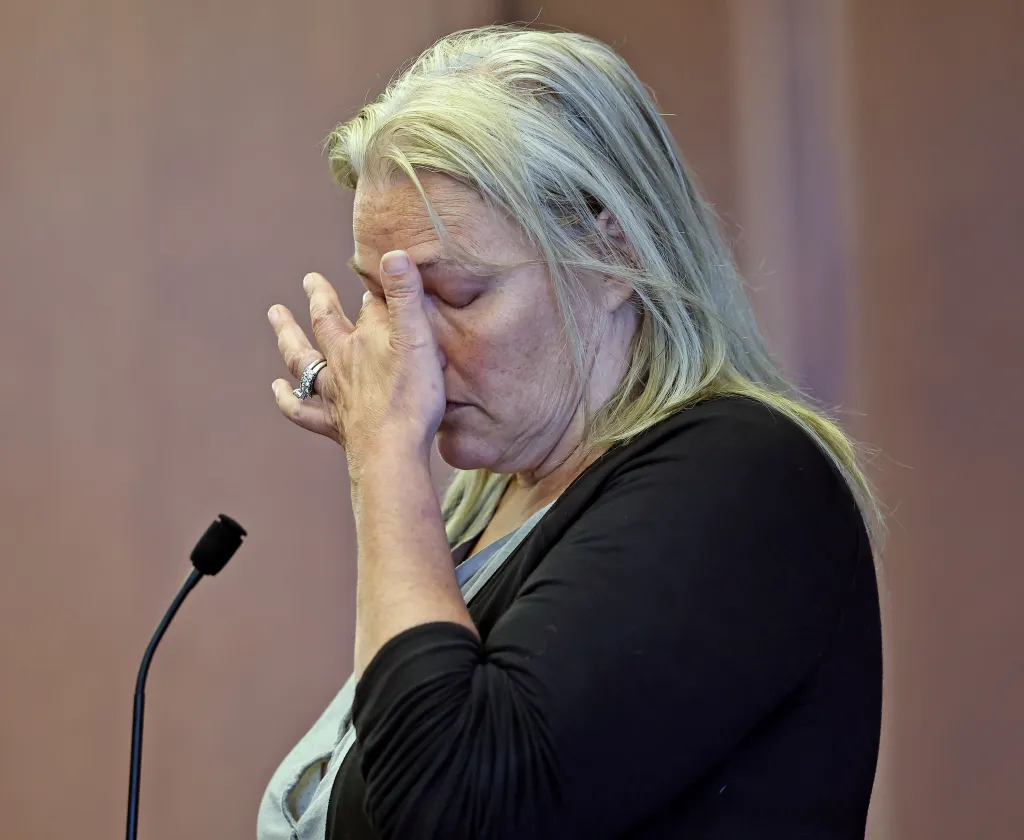 Dawn Light, with long blonde hair, covers her eyes with her right hand in a courtroom.