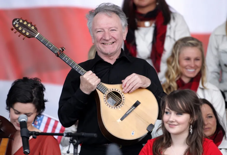 Donal Lunny mỉm cười và cầm cây đàn bouzouki, xung quanh là các nhạc sĩ khác.