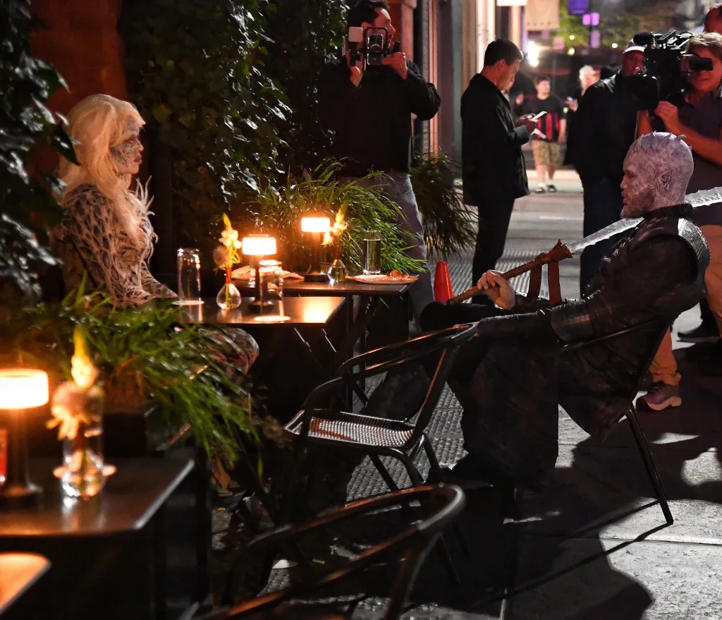 Jordyn Woods and Karl-Anthony Towns dressed in Game of Thrones costumes while sitting at an outdoor table at night.