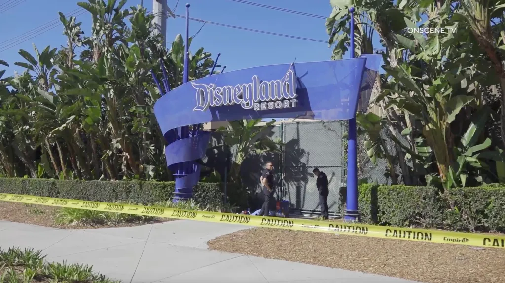 Two police officers stand behind caution tape at a Disneyland Resort entrance.