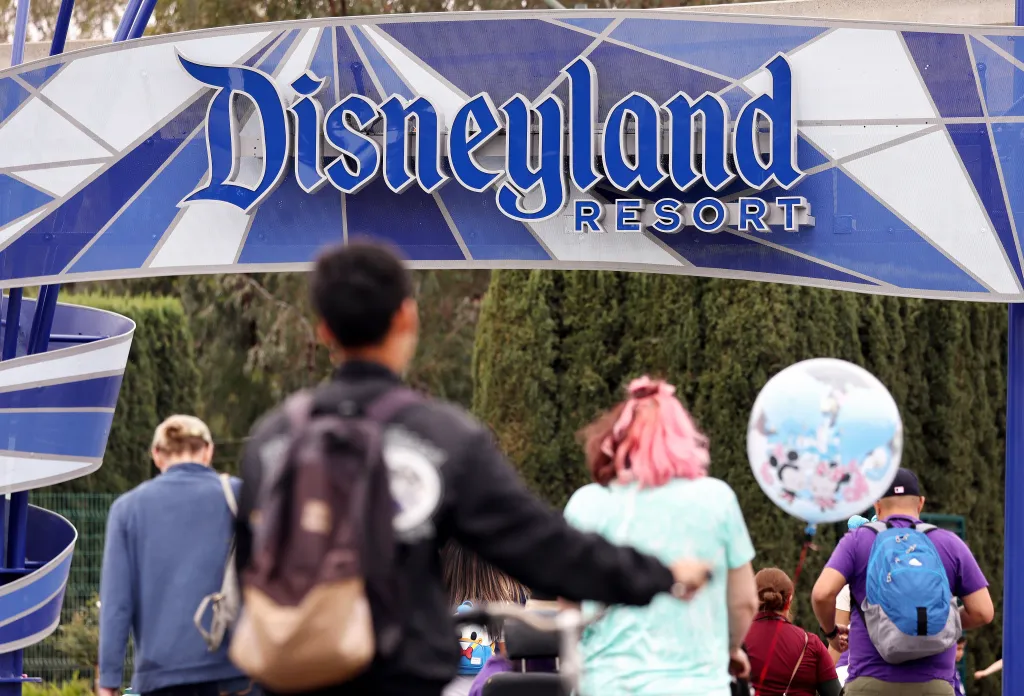 Visitors walking toward the Disneyland Resort entrance sign.