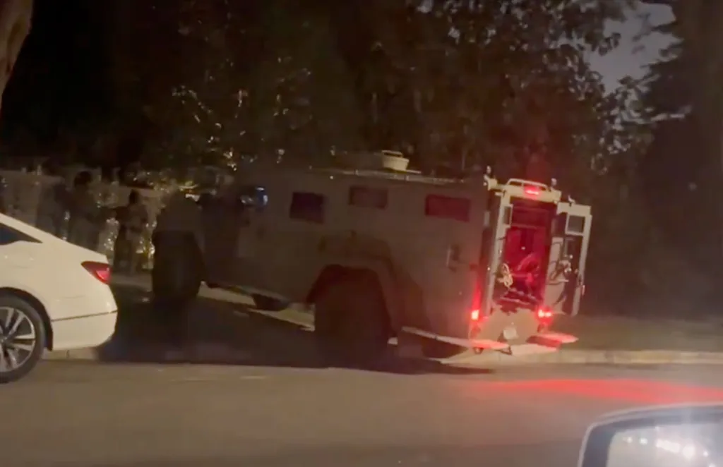 Law enforcement tactical vehicle parked at a Beverly Hills mansion during a federal raid.
