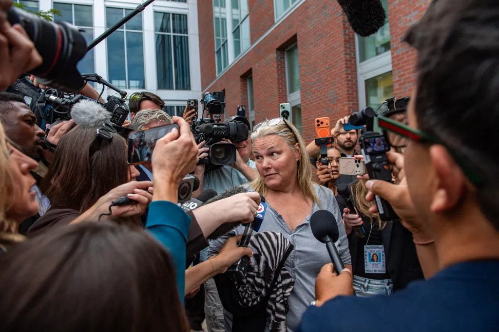 Dawn Light, charged with witness intimidation, is surrounded by reporters holding microphones and cameras outside Plymouth Superior Court.