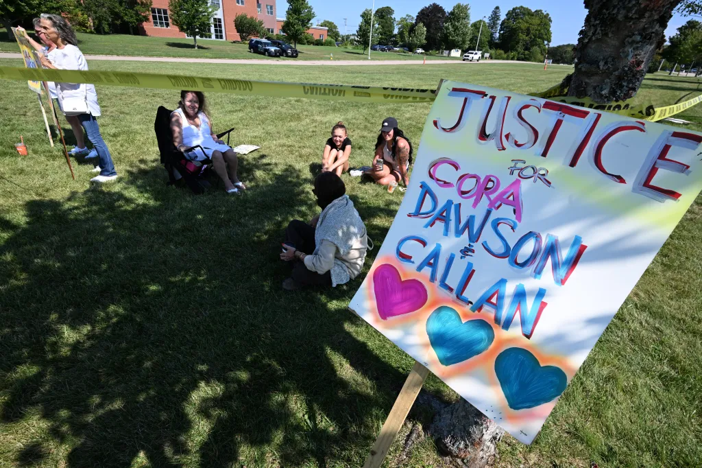 Women hold signs calling for justice for the Clancy children outside Plymouth Superior Court.