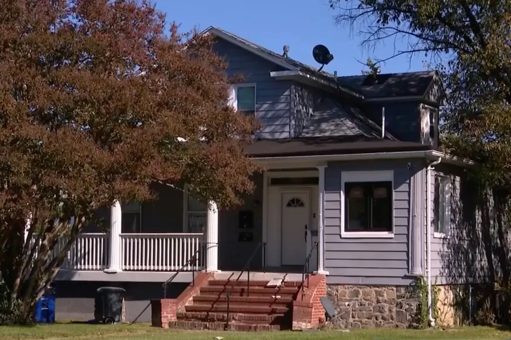 A two-story gray house with a front porch, white railings, and brick steps.