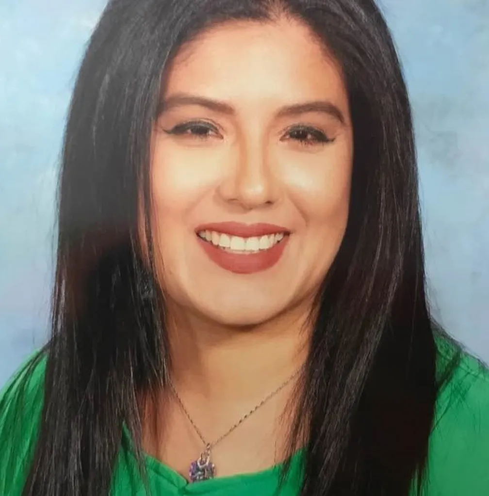 Pamela Cisneros with long dark hair, smiling and wearing a green top.