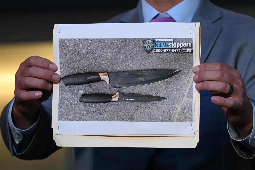 PH๏τo of two knives recovered at a crime scene, held up by an officer.