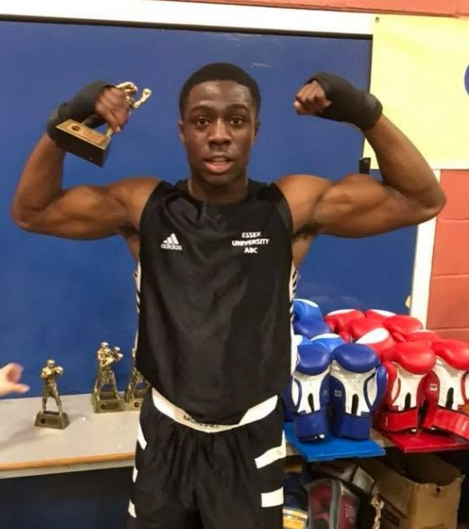 James Abiwon tạo dáng trong bộ đồ boxing cùng với chiếc cúp và băng quấn tay.