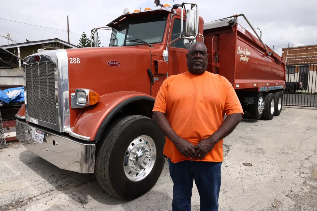 Kenyatta Cole standing in front of an orange dump truck.