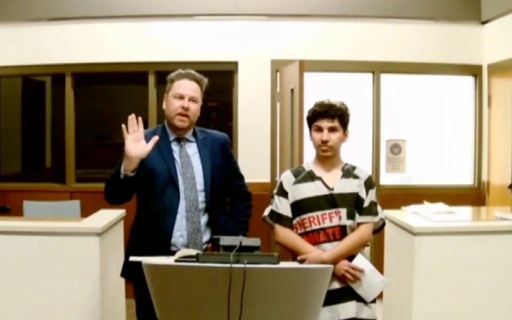 Adrian Ayala, in a striped inmate uniform, stands in court next to his attorney.