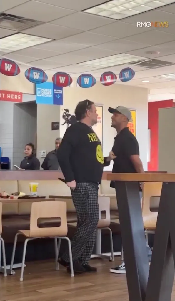 A man in a baseball hat confronts another man holding a knife inside a fast food restaurant.