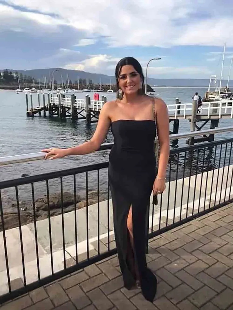 Tayla Brailey posing by the water in a black dress.