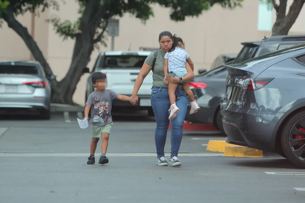 Wendy Clemente walks through a parking lot with her two children.