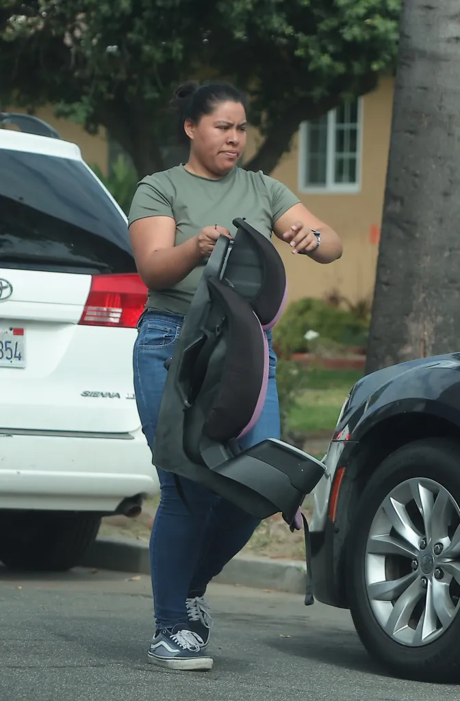 Wendy Clemente carrying a child car seat between vehicles.
