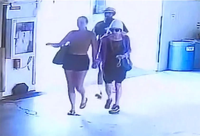 Surveillance footage of three people walking inside a parking garage.