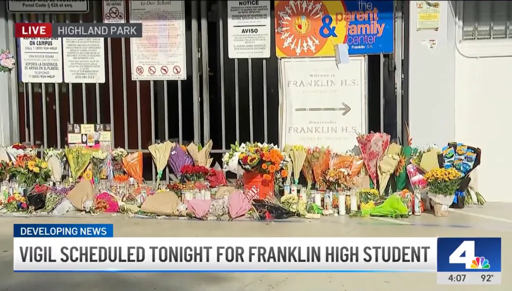 A memorial with flowers and candles is set up in front of Franklin High School.