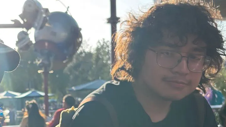 Portrait of Xavier Nungarary with curly hair and glasses.