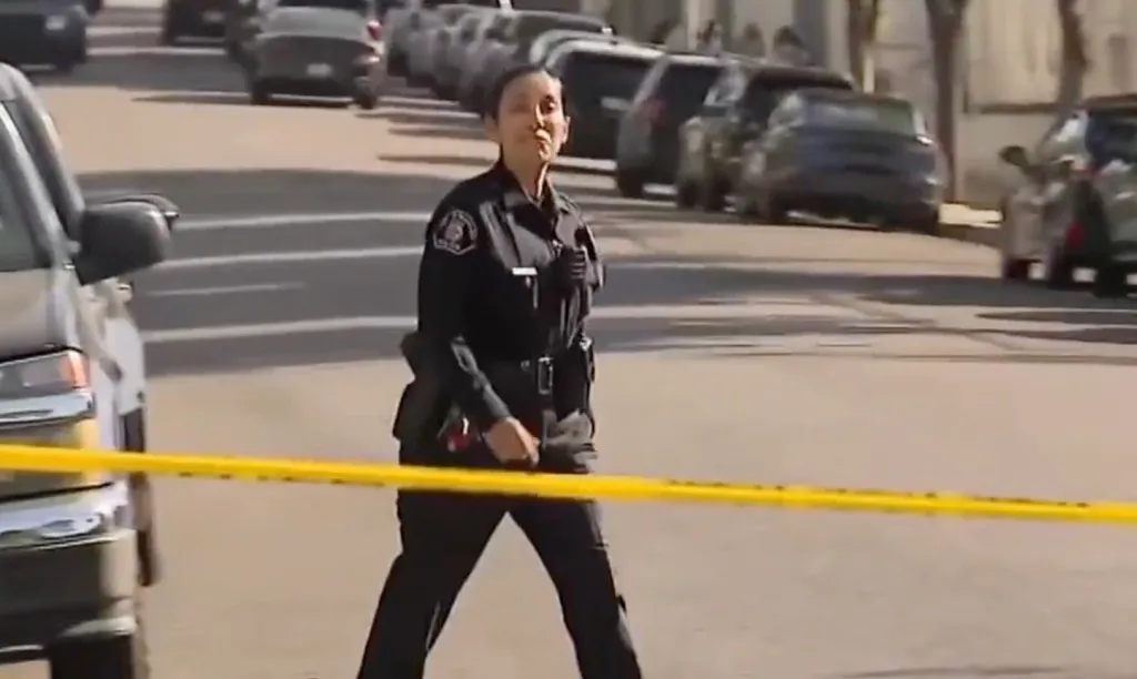 A police officer at the scene of the student's death in Highland Park behind yellow police tape.