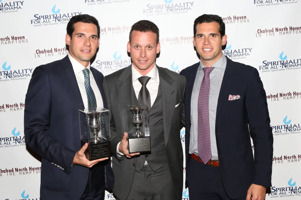 Oren Alexander, Tal Alexander, and Alon Alexander pose together holding awards at an event.