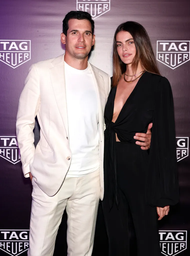 Oren Alexander stands next to a woman in front of a TAG Heuer backdrop.