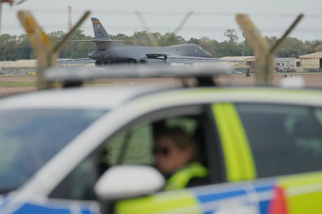 A B1 bomber at RAF Fairford air base, viewed past a police vehicle and a security checkpoint.