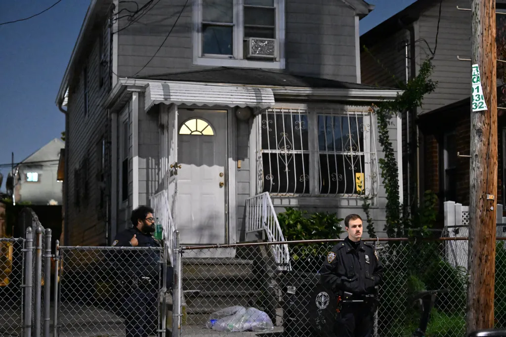 NYPD officers stand outside a two-story home in Queens where an 81-year-old woman was found unresponsive.