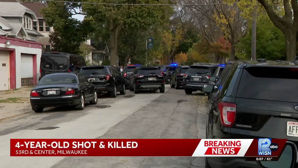 Numerous police cars and a van line a residential street with houses, where a 4-year-old was shot and killed.