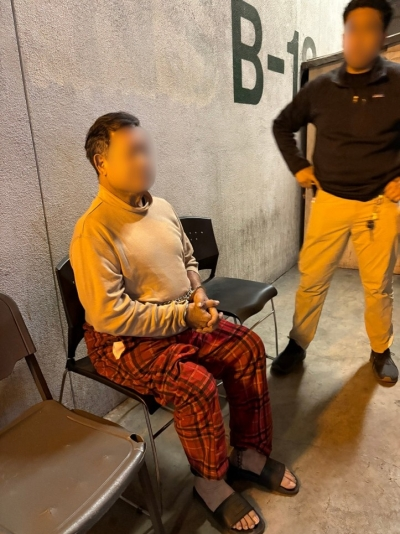 Omar Alexander Muñoz sitting in a chair with his hands cuffed in front of him.