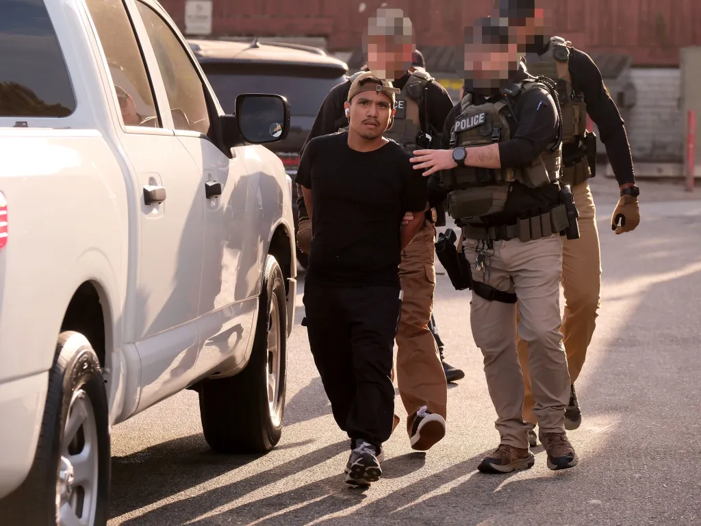 HSI agents escort Darwin Rivera-Flores in handcuffs during a raid in Winnetka, California.