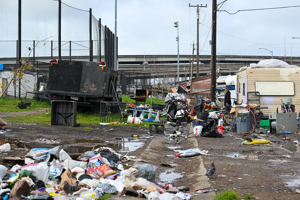A view of a homeless encampment with debris and trash on a street in West Oakland, California.