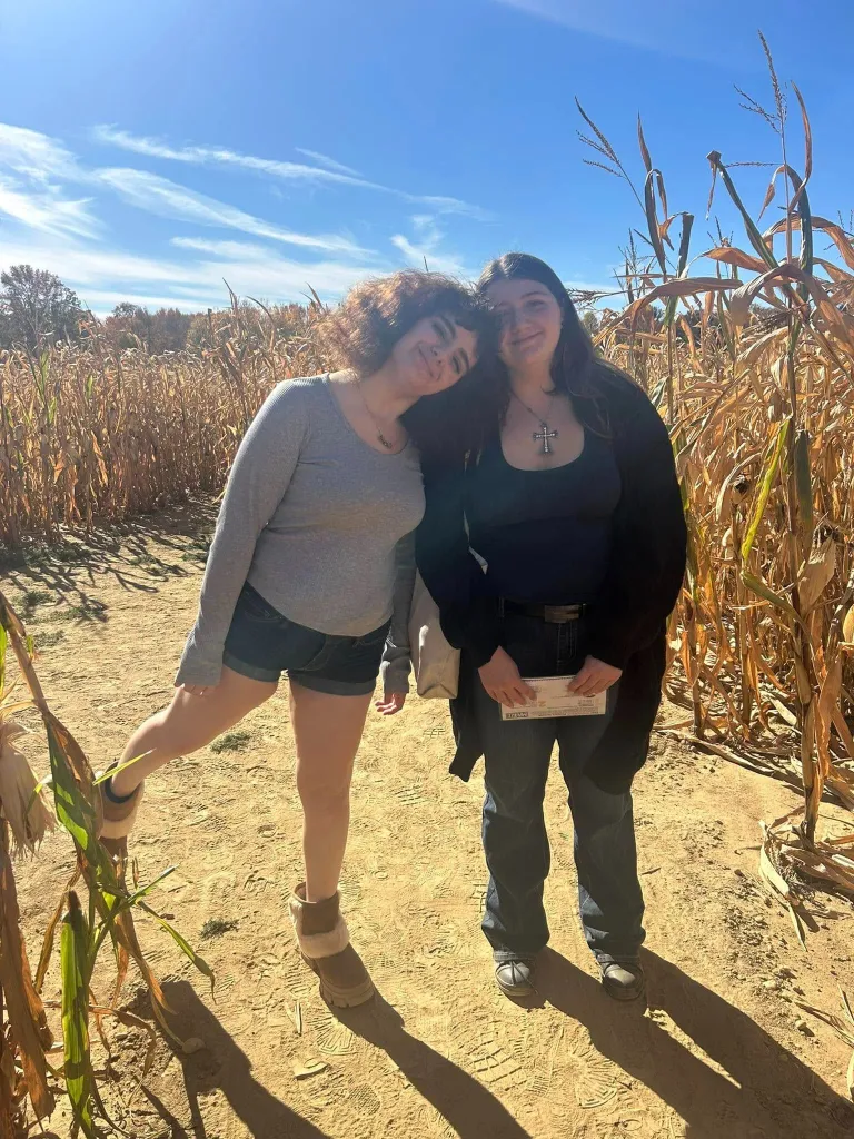 Maria Niotis and Isabella Salas stand smiling together in a cornfield.