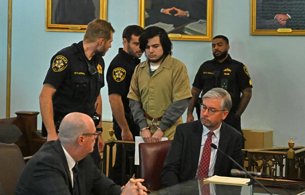 Vincent Battiloro in handcuffs at his arraignment in Union County Court, flanked by sheriff's officers.