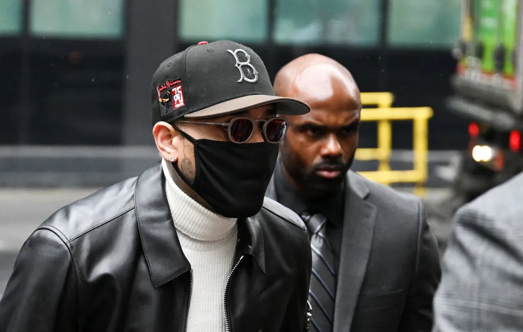 US singer Chris Brown wearing a black face mask, cap, and leather jacket arrives at Southwark Crown Court in London.
