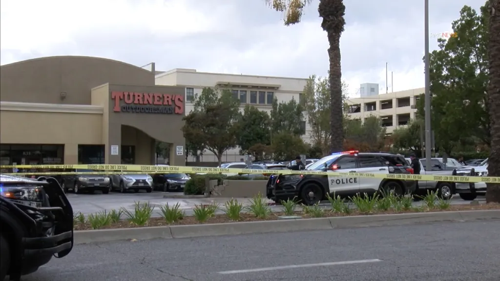 Police cars and yellow crime scene tape outside a Turner's Outdoorsman store.