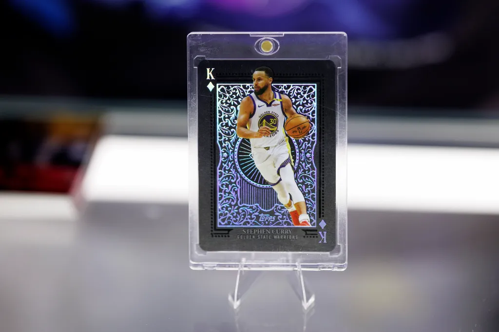 A Stephen Curry trading card in a protective case displayed on a stand.
