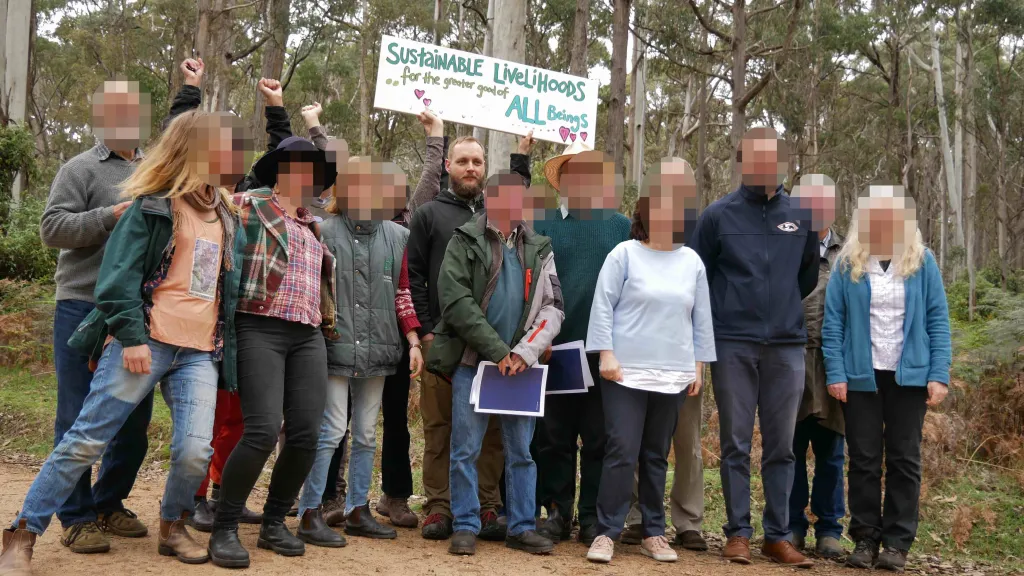 Brendan Nugent and fellow campaigners at a forest conservation protest, holding a sign that reads "Sustainable Livelihoods for the Greater Good of All Beings."