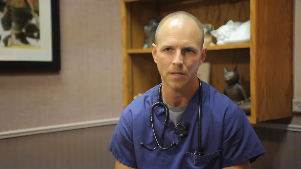 Bryan Schmidt wearing blue scrubs with a stethoscope around his neck.