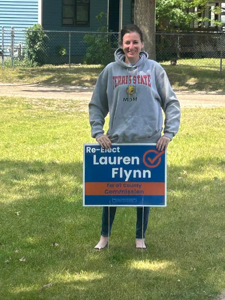 Grand Traverse County Commissioner Lauren Flynn holding a campaign sign.