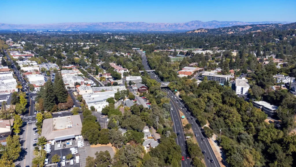 Aerial view of Highway 17 cutting through Downtown Los Gatos, California, with surrounding commercial buildings, neighborhoods, and trees.