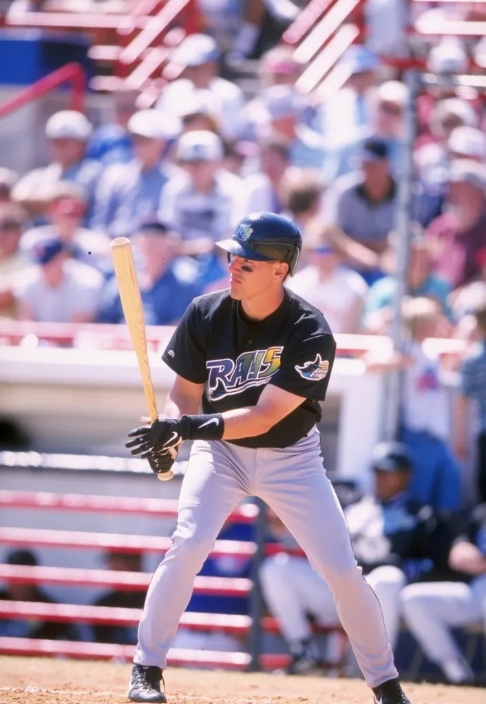 Rich Butler standing at home plate holding a bat, wearing a black jersey and helmet.