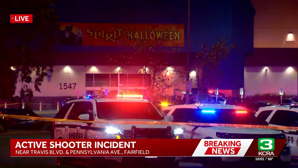 Police vehicles with flashing lights outside a Spirit Halloween store during an active shooter incident.